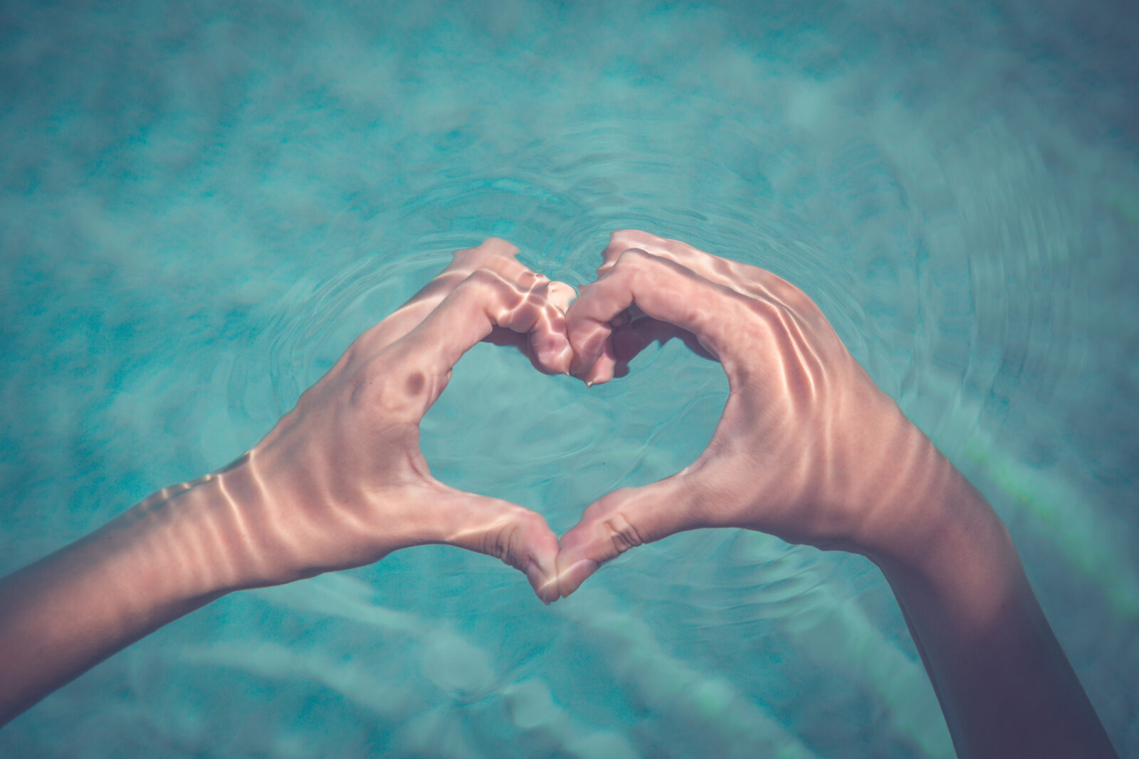 A picture of hands forming a heart over a body of water, for an LCA post on showing your water love on Valentine's Day.