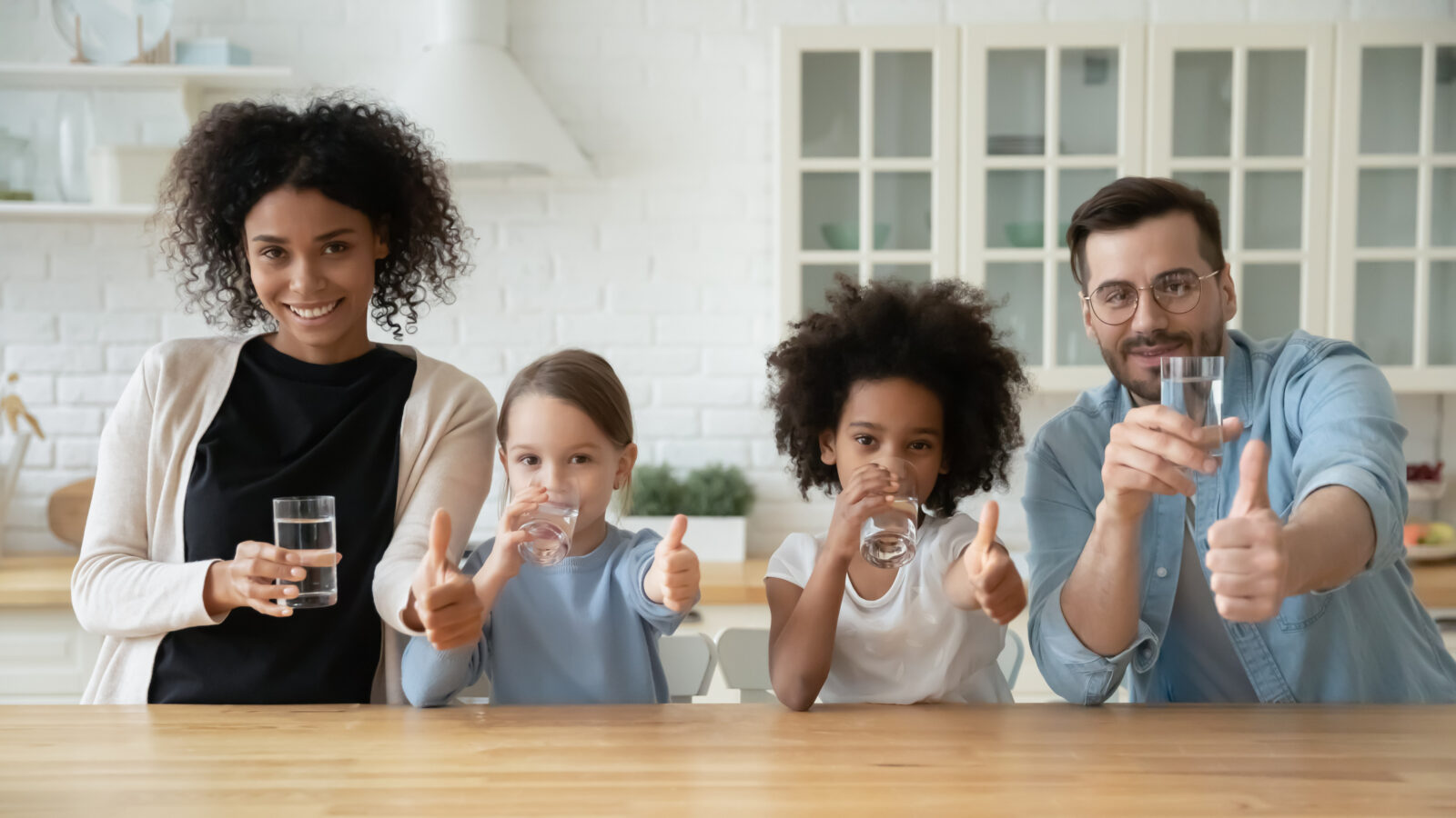 A picture of a multiracial family holding glasses of water, to illustrate a Lehigh County Authority blogpost on National Water Quality Month.