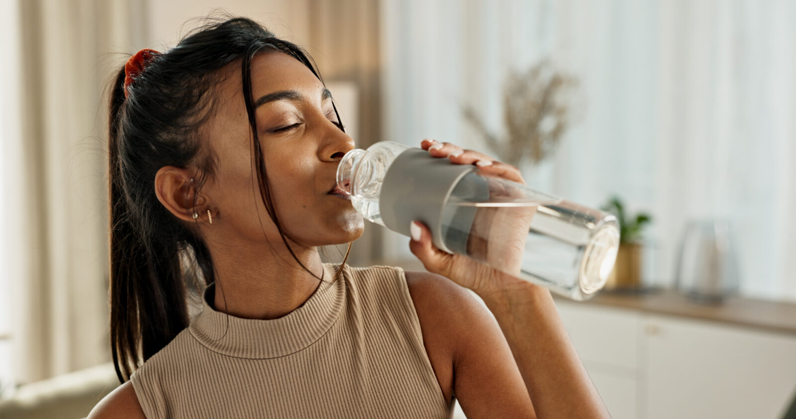 A woman takes a sip of water from a refillable clear bottle. Access to clean, safe water is why LCA is joining the American Water Works Association in celebrating Drinking Water Week from May 4-10.